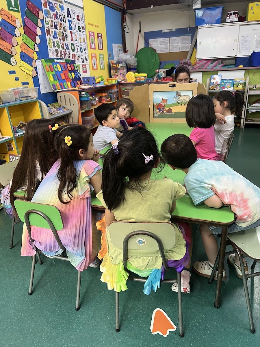 Niños del jardín infantil trabajan en mesas dentro de una sala decorada con sus trabajos